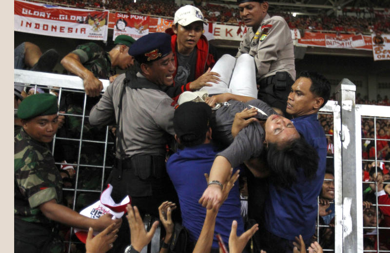 tragedysea Indonesian police officers evacuate an unconscious woman from the crowd after a stampede inside the stadium during the Southeast Asian Games final soccer match between Indonesia and Malaysia at Gelora Bung Karno stadium in Jakarta, Indonesia, Monday, Nov. 21, 2011. A stampede outside the stadium at the football final of the Southeast Asian Games has left two fans dead.
