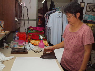 he wife of the owner of the Kedai Dobi Shanghai using an old antique iron to iron laundries, who says that it is better than modern iron, despite it’s heavy weight.