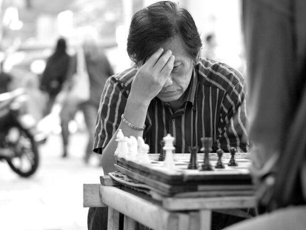 A moment of hesitation captured as a man ponders over his next move in a game of chess.