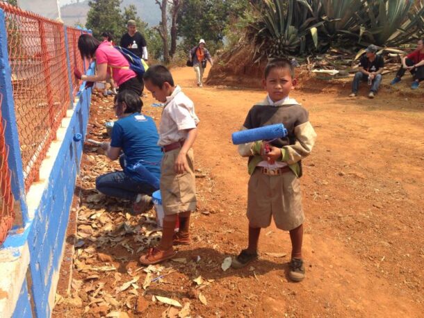 The children and World Vision Malaysia helping to paint a fence at a school in Thailand.
