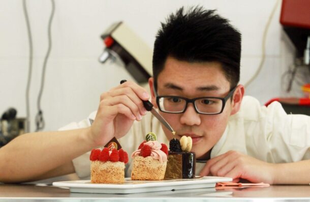 Lim putting a gold leaf on his Mousse au<br>Chocolat – a chocolate sponge cake with<br>
dark chocolate mousse, hazelnut crunch and<br>
a mirror glaze.