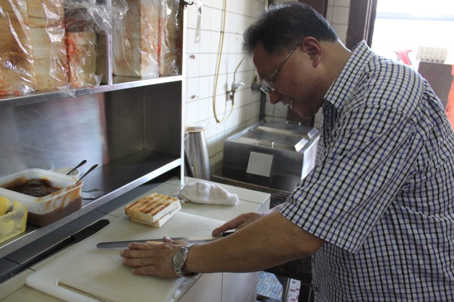 David demonstrates how the workers at Restoran Hua Mui toast bread on a charcoal grill.