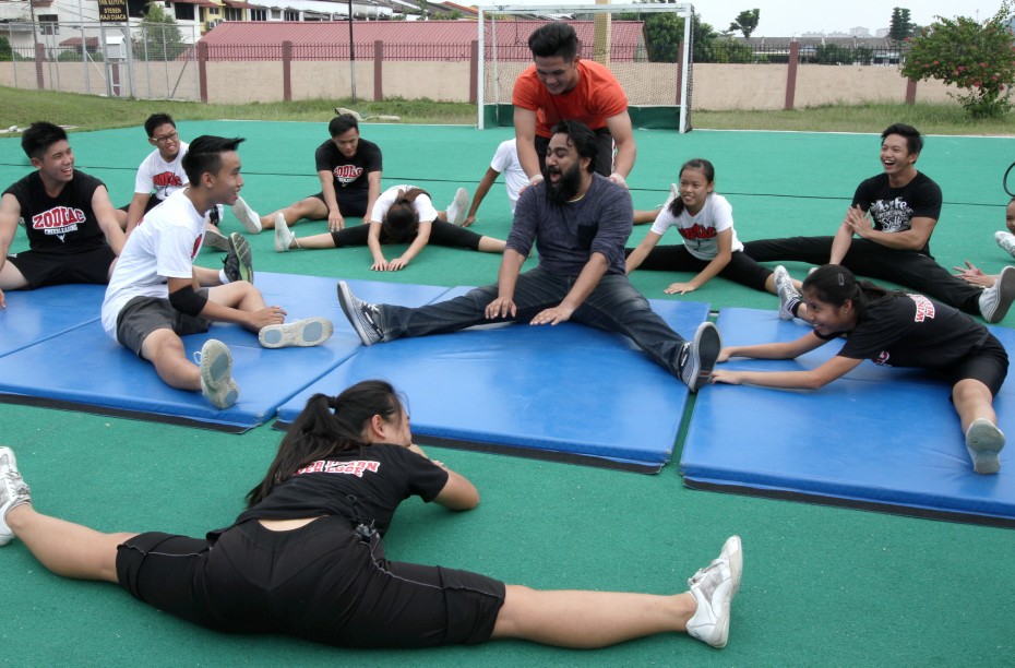 Prakash struggles during warm up before attempting the "toe touch" move. Notice the difference in flexibility...<br>- Photo: SAMUEL ONG / The Star