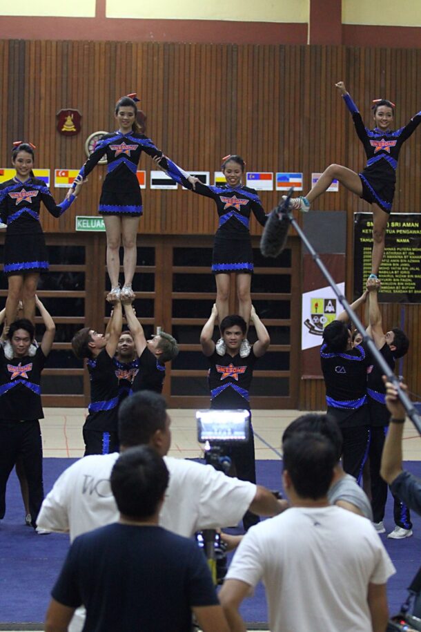 Shooting is hard work, but the cheerleaders never complained, tumbling and stunting take after take.